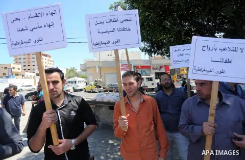 Palestinians hold placards during a protest against a power cut and the Israeli blockade of the Gaza Strip, in Gaza city on May 8, 2016. Photo by Mohammed Asad