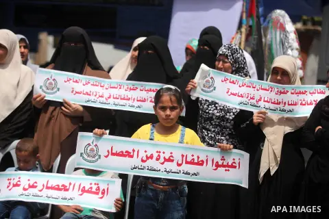 Palestinian children hold placards during a protest against the killing of three boys from the al-Hindi family, who died in a fire caused by a candle at the family home in Gaza city on May 9, 2016. Photo by Ashraf Amra