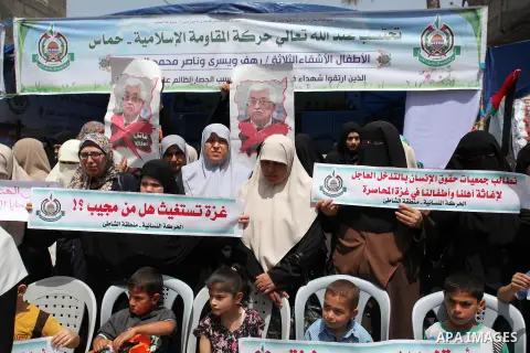 Palestinian children hold placards during a protest against the killing of three boys from the al-Hindi family, who died in a fire caused by a candle at the family home in Gaza city on May 9, 2016. Photo by Ashraf Amra