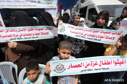Palestinian children hold placards during a protest against the killing of three boys from the al-Hindi family, who died in a fire caused by a candle at the family home in Gaza city on May 9, 2016. Photo by Ashraf Amra