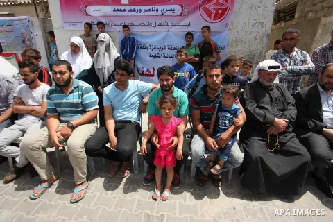 Palestinian children hold placards during a protest against the killing of three boys from the al-Hindi family, who died in a fire caused by a candle at the family home in Gaza city on May 9, 2016. Photo by Ashraf Amra