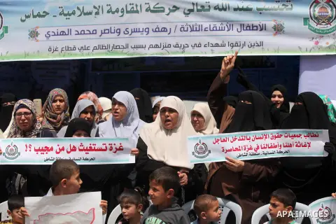 Palestinian children hold placards during a protest against the killing of three boys from the al-Hindi family, who died in a fire caused by a candle at the family home in Gaza city on May 9, 2016. Photo by Ashraf Amra