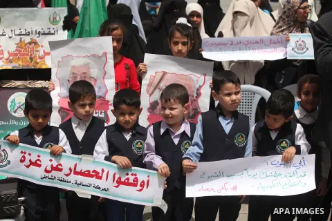 Palestinian children hold placards during a protest against the killing of three boys from the al-Hindi family, who died in a fire caused by a candle at the family home in Gaza city on May 9, 2016. Photo by Ashraf Amra