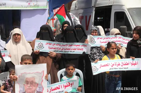 Palestinian children hold placards during a protest against the killing of three boys from the al-Hindi family, who died in a fire caused by a candle at the family home in Gaza city on May 9, 2016. Photo by Ashraf Amra