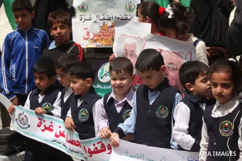 Palestinian children hold placards during a protest against the killing of three boys from the al-Hindi family, who died in a fire caused by a candle at the family home in Gaza city on May 9, 2016. Photo by Ashraf Amra