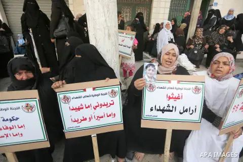 Palestinian families of martyrs, hold banners during a protest to demand their salaries, in Gaza city, on May 10, 2016. Photo by Mohammed Asad