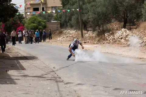 A Palestinian protester hurls a tear gas canister back towards Israeli security forces during clashes following a demonstration against the expropriation of Palestinian land by Israel, on May 13, 2016 in the village of K...