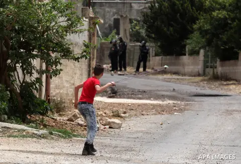 A Palestinian protester uses a slingshot to hurl stones towards Israeli security forces during clashes following a demonstration against the expropriation of Palestinian land by Israel, on May 13, 2016 in the village of...
