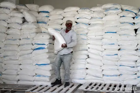 A Palestinian man carries a bag of flour to distribute to families, at an aid distribution centre of the United Nations Relief and Works Agency (UNRWA) in the southern Gaza Strip town of Khan Younis on May 15, 2016, on t...