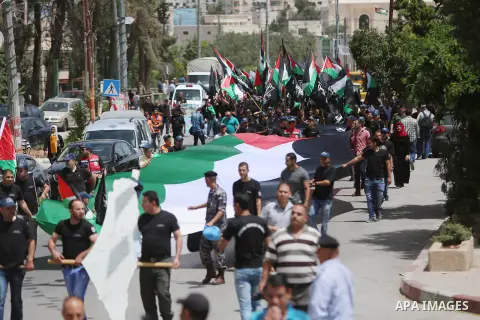 Palestinians hold a flag during in a procession on the 68th anniversary of the "Nakba" in the West Bank city of Ramallah on May 15, 2016. "Nakba" means in Arabic "catastrophe" in reference to the birth of the state of Is...