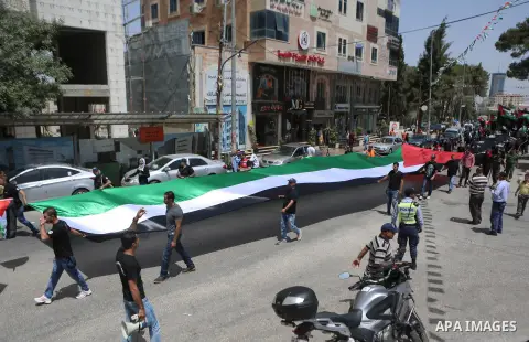 Palestinians hold a flag during in a procession on the 68th anniversary of the "Nakba" in the West Bank city of Ramallah on May 15, 2016. "Nakba" means in Arabic "catastrophe" in reference to the birth of the state of Is...