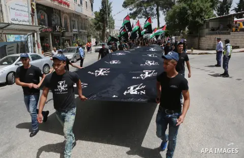 Palestinians hold a flag during in a procession on the 68th anniversary of the "Nakba" in the West Bank city of Ramallah on May 15, 2016. "Nakba" means in Arabic "catastrophe" in reference to the birth of the state of Is...