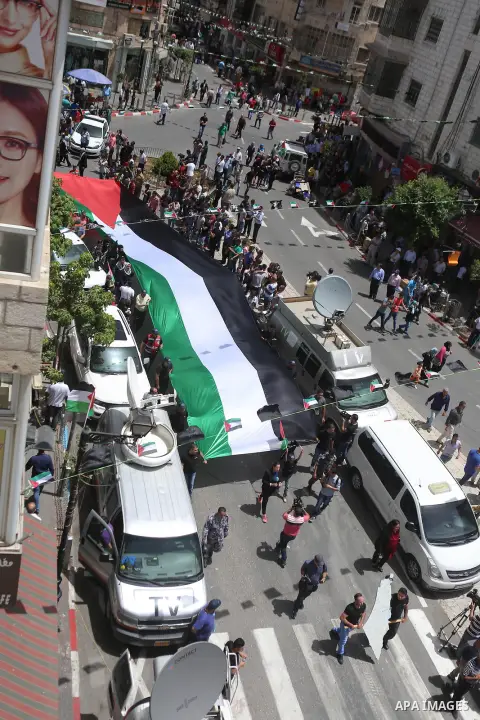 Palestinians hold a flag during in a procession on the 68th anniversary of the "Nakba" in the West Bank city of Ramallah on May 15, 2016. "Nakba" means in Arabic "catastrophe" in reference to the birth of the state of Is...