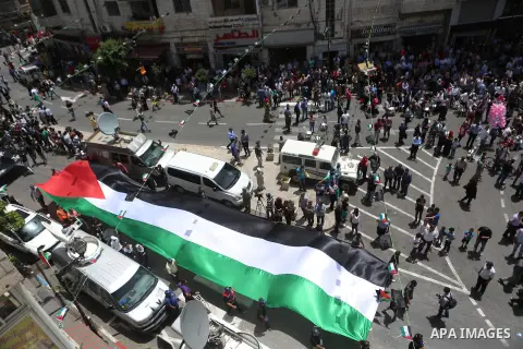 Palestinians hold a flag during in a procession on the 68th anniversary of the "Nakba" in the West Bank city of Ramallah on May 15, 2016. "Nakba" means in Arabic "catastrophe" in reference to the birth of the state of Is...