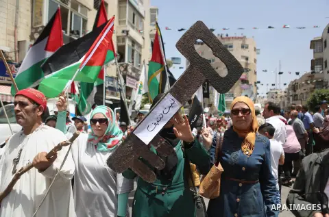 Palestinians hold a flag during in a procession on the 68th anniversary of the "Nakba" in the West Bank city of Ramallah on May 15, 2016. "Nakba" means in Arabic "catastrophe" in reference to the birth of the state of Is...