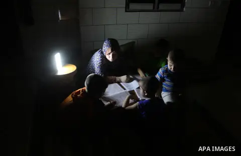 Palestinian boys study on lanterns light during a power outage in Rafah in the southern Gaza Strip on May 18, 2016. Photo by Abed Rahim Khatib