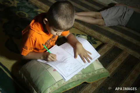 Palestinian boys study on lanterns light during a power outage in Rafah in the southern Gaza Strip on May 18, 2016. Photo by Abed Rahim Khatib
