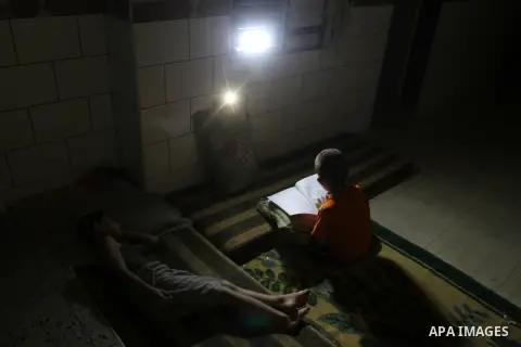 Palestinian boys study on lanterns light during a power outage in Rafah in the southern Gaza Strip on May 18, 2016. Photo by Abed Rahim Khatib