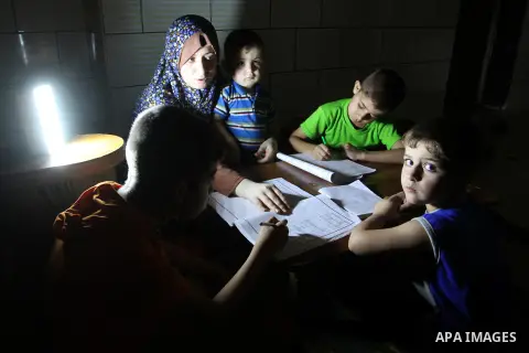 Palestinian boys study on lanterns light during a power outage in Rafah in the southern Gaza Strip on May 18, 2016. Photo by Abed Rahim Khatib