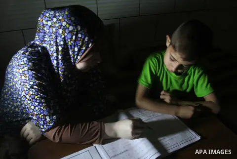 Palestinian boys study on lanterns light during a power outage in Rafah in the southern Gaza Strip on May 18, 2016. Photo by Abed Rahim Khatib