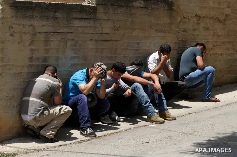 Palestinian protesters take cover from tear gas fired by Israeli security forces during clashes following a demonstration against the expropriation of Palestinian land by Israel, on May 20, 2016 in the village of Kfar Qa...