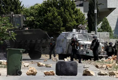 Israeli security forces stand guard next to their armoured vehicle during clashes with Palestinians following a demonstration against the expropriation of Palestinian land by Israel, on May 20, 2016 in the village of Kfa...