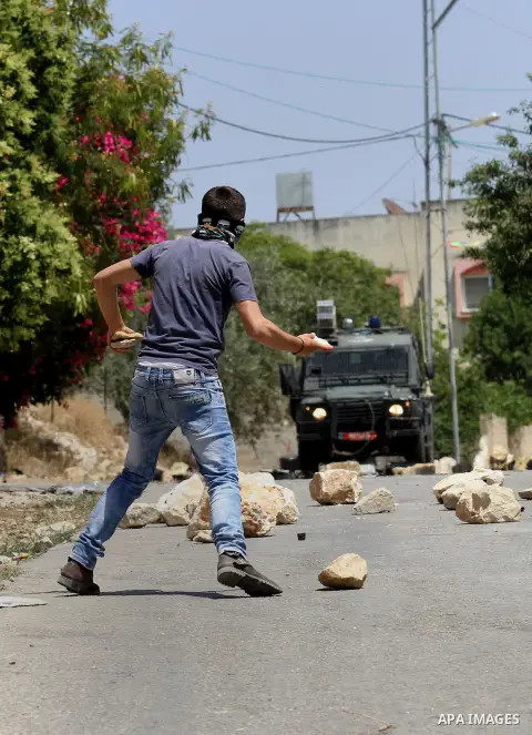 A Palestinian protester uses a slingshot to throw stones towards Israeli security forces during clashes following a demonstration against the expropriation of Palestinian land by Israel, on May 20, 2016 in the village of...