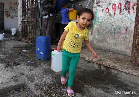 Palestinian children fill plastic bottles and jerry cans with drinking water from a public tap in Rafah in the southern Gaza strip, on May 22, 2016. Photo by Abed Rahim Khatib