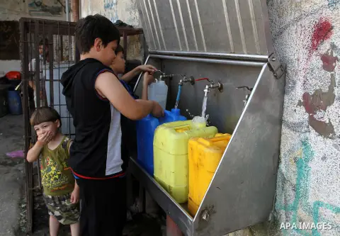 Palestinian children fill plastic bottles and jerry cans with drinking water from a public tap in Rafah in the southern Gaza strip, on May 22, 2016. Photo by Abed Rahim Khatib