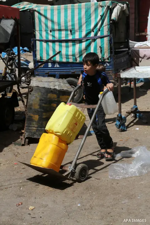 A Palestinian child rides a cart carrying cans filled with drinking water from a public tap in Rafah in the southern Gaza strip, on May 22, 2016. Photo by Abed Rahim Khatib