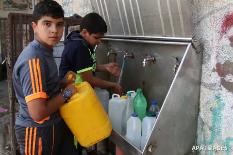 Palestinian children fill plastic bottles and jerry cans with drinking water from a public tap in Rafah in the southern Gaza strip, on May 22, 2016. Photo by Abed Rahim Khatib