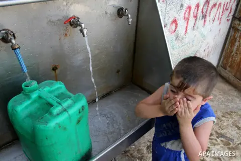 Palestinian children fill plastic bottles and jerry cans with drinking water from a public tap in Rafah in the southern Gaza strip, on May 22, 2016. Photo by Abed Rahim Khatib