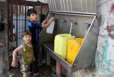Palestinian children fill plastic bottles and jerry cans with drinking water from a public tap in Rafah in the southern Gaza strip, on May 22, 2016. Photo by Abed Rahim Khatib