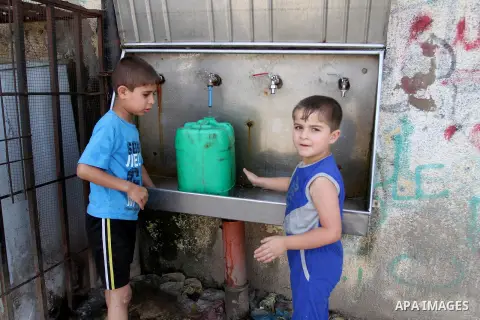 Palestinian children fill plastic bottles and jerry cans with drinking water from a public tap in Rafah in the southern Gaza strip, on May 22, 2016. Photo by Abed Rahim Khatib