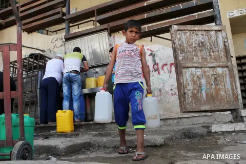Palestinians fill plastic bottles and jerry cans with drinking water from a public tap in Rafah in the southern Gaza strip, on May 22, 2016. Photo by Abed Rahim Khatib