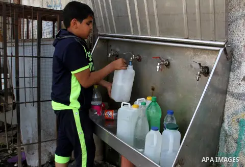 Palestinian children fill plastic bottles and jerry cans with drinking water from a public tap in Rafah in the southern Gaza strip, on May 22, 2016. Photo by Abed Rahim Khatib
