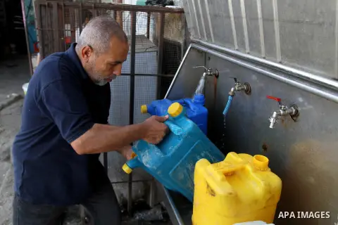 A Palestinian man fills plastic bottles and jerry cans with drinking water from a public tap in Rafah in the southern Gaza strip, on May 22, 2016. Photo by Abed Rahim Khatib
