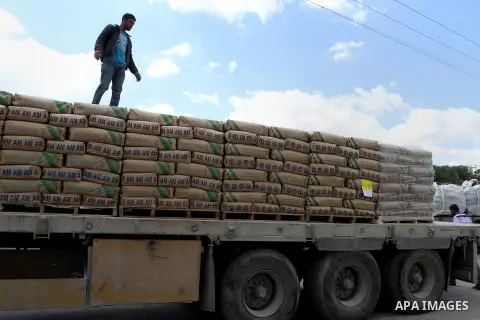 A Palestinian worker stands on a truck loaded with bags of cement after it entered the southern Gaza Strip from Israel through the Kerem Shalom crossing in Rafah on May 23, 2016. Israel said on May 22 it was lifting a ba...