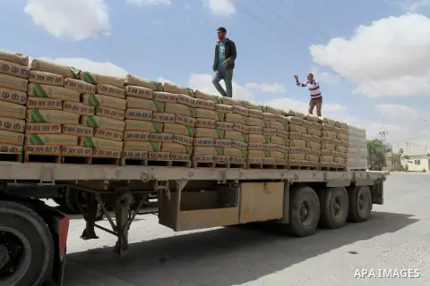 Palestinian workers stand on a truck loaded with bags of cement after it entered the southern Gaza Strip from Israel through the Kerem Shalom crossing in Rafah on May 23, 2016. Israel said on May 22 it was lifting a ban...