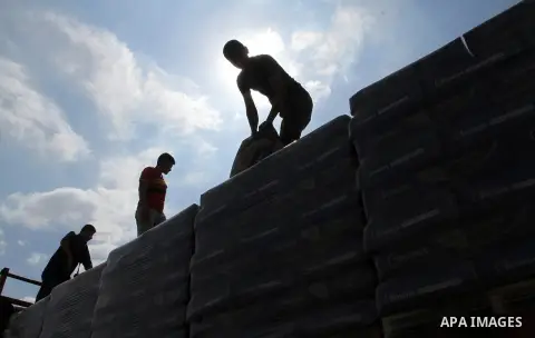 Palestinian workers stand on a truck loaded with bags of cement after it entered the southern Gaza Strip from Israel through the Kerem Shalom crossing in Rafah on May 23, 2016. Israel said on May 22 it was lifting a ban...