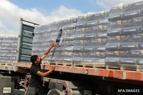 Palestinian workers stand on a truck loaded with bags of cement after it entered the southern Gaza Strip from Israel through the Kerem Shalom crossing in Rafah on May 23, 2016. Israel said on May 22 it was lifting a ban...