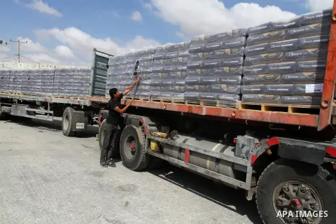Palestinian workers stand on a truck loaded with bags of cement after it entered the southern Gaza Strip from Israel through the Kerem Shalom crossing in Rafah on May 23, 2016. Israel said on May 22 it was lifting a ban...
