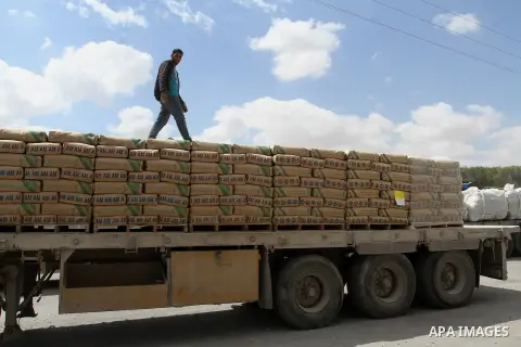 A Palestinian worker stands on a truck loaded with bags of cement after it entered the southern Gaza Strip from Israel through the Kerem Shalom crossing in Rafah on May 23, 2016. Israel said on May 22 it was lifting a ba...