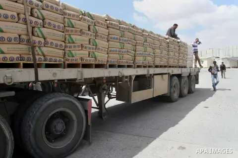 A Palestinian worker stands on a truck loaded with bags of cement after it entered the southern Gaza Strip from Israel through the Kerem Shalom crossing in Rafah on May 23, 2016. Israel said on May 22 it was lifting a ba...