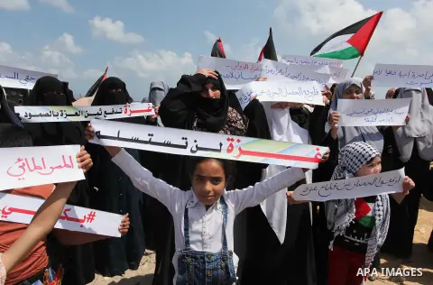 Palestinians hold placards during a protest against the Israeli blockade of the Gaza Strip at the Gaza seaport, on May 24, 2016. Photo by Ashraf Amra
