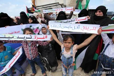 Palestinians hold placards during a protest against the Israeli blockade of the Gaza Strip at the Gaza seaport, on May 24, 2016. Photo by Ashraf Amra