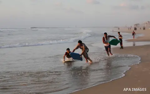 Palestinian youths enjoy a day at the beach of the Mediterranean sea on the coast of Gaza city during sunset, on May 24, 2016. Photo by Mohammed Asad
