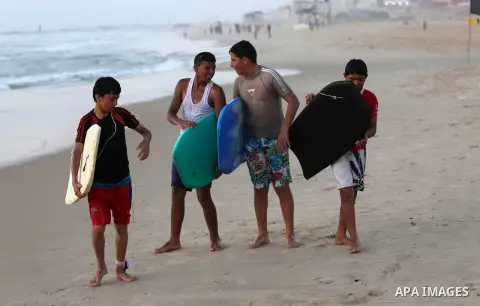 Palestinian youths enjoy a day at the beach of the Mediterranean sea on the coast of Gaza city during sunset, on May 24, 2016. Photo by Mohammed Asad