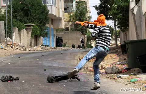 A Palestinian protester uses a slingshot to throw stones towards Israeli security forces during clashes following a demonstration against the expropriation of Palestinian land by Israel, on May 27, 2016 in the village of...