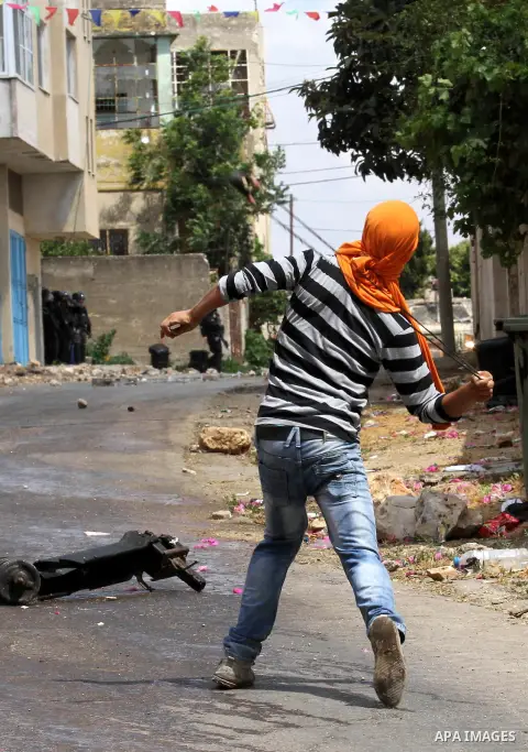 A Palestinian protester uses a slingshot to throw stones towards Israeli security forces during clashes following a demonstration against the expropriation of Palestinian land by Israel, on May 27, 2016 in the village of...